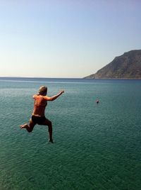 Rear view full length of woman jumping into sea