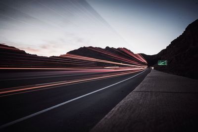 Light trails on road against sky