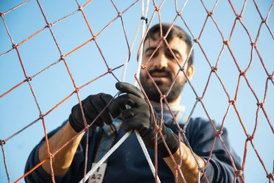 Low angle view portrait of chainlink fence against sky