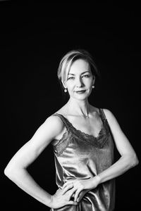 Portrait of woman standing against black background