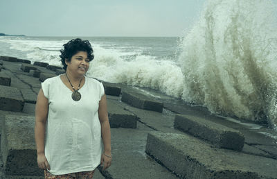 Portrait of woman standing by sea against sky