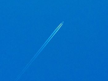 Low angle view of vapor trails against clear blue sky