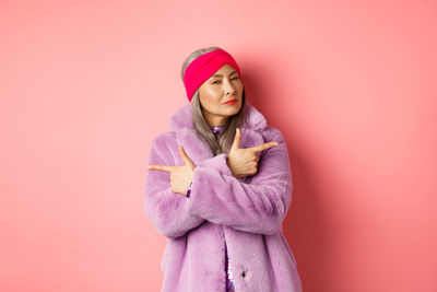 Woman standing against pink background