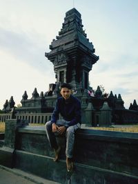 Portrait of man sitting against built structure