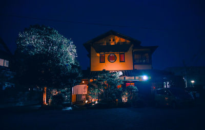 Illuminated building by street against sky at night