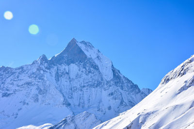 Scenic view of snowcapped mountains against clear blue sky