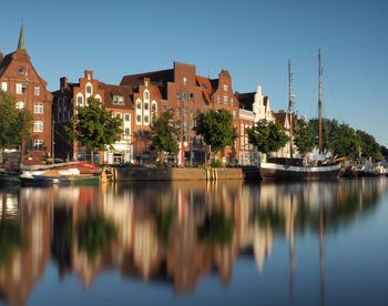 Canal by buildings against sky in city