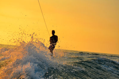 Man kiteboarding on sea against clear sky during sunset