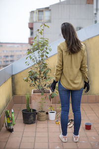 Rear view of woman standing by potted plants