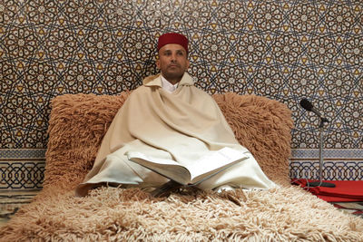 Full length of man sitting on sofa against wall