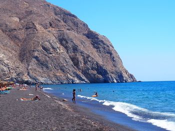 People on beach against clear sky