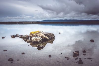 Reflection of rocks in lake against sky