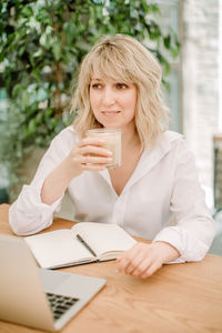 Portrait of smiling woman with coffee cup on table