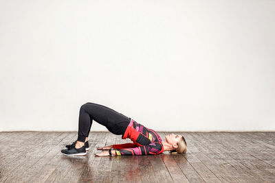 Young woman lying on floor against wall