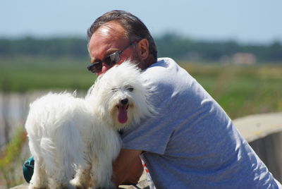 Mature man with dog sticking out tongue on retaining wall