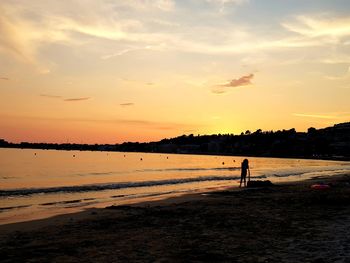 Silhouette people on beach against sky during sunset