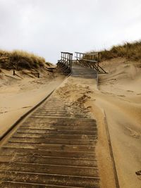 Boardwalk leading towards beach against sky