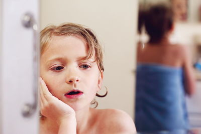 Close-up of boy wrapped in towel at bathroom against mirror