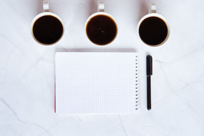 Businessman working morning with notebook, cups of hot coffee on white background. top. flat lay