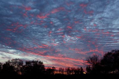 Low angle view of silhouette trees against dramatic sky