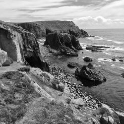 Scenic view of cliff by sea against sky