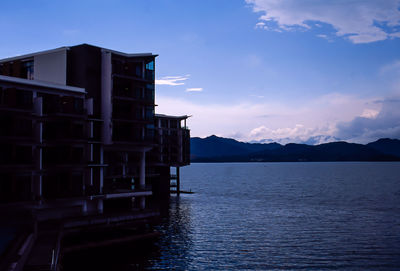 Building by sea against sky during sunset