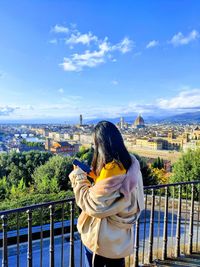 Rear view of woman standing by railing against cityscape