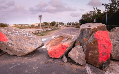 Garbage on rock by road against sky