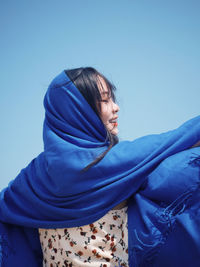 Portrait of young woman standing against clear sky