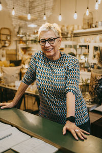 Portrait of senior female owner standing at checkout counter in store