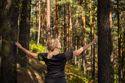 Beautiful woman walking through the forest, idea of restoring health and relaxation, forest bath