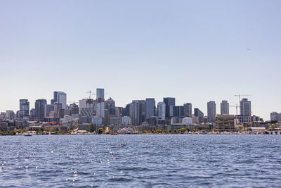 Sea by modern buildings against clear sky