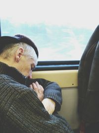 Close-up of man sleeping while leaning on window in bus