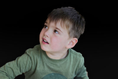 Portrait of cute boy against black background