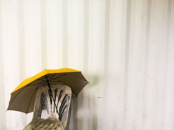 Close-up of yellow umbrella on wall during rainy season