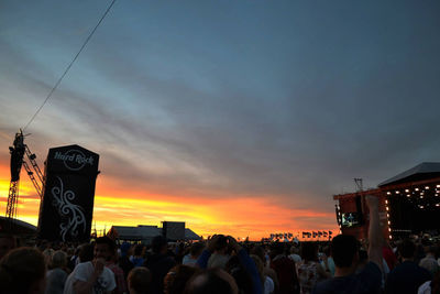 People at music concert against sky during sunset