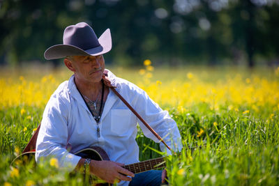 Rear view of man with guitar in field