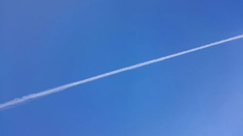 Low angle view of vapor trails against blue sky
