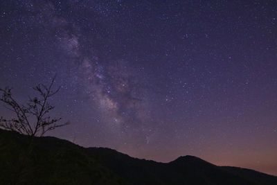 Silhouette mountain against star field at night