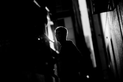 Silhouette man standing at alley during night