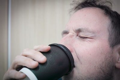 Close-up of man with eyes closed drinking coffee