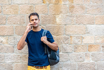 Portrait of teenage boy standing against brick wall