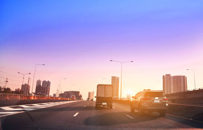Cars on highway in city at sunset