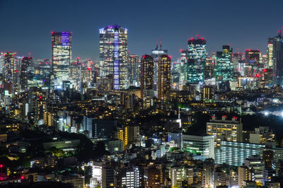 Illuminated cityscape against sky at night