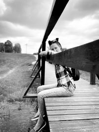 Portrait of woman sitting on wood against sky