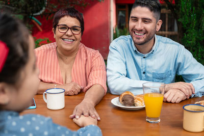 Smiling friends sitting on table