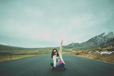 Woman gesturing while sitting on road in city