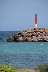 Lighthouse by sea against sky