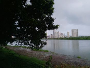 Scenic view of river by buildings against sky