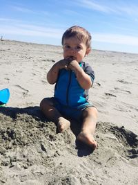 Portrait of boy playing on beach against sky